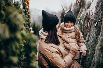 Winter holidays and people concept - happy family with little daughter choosing Xmas tree at...