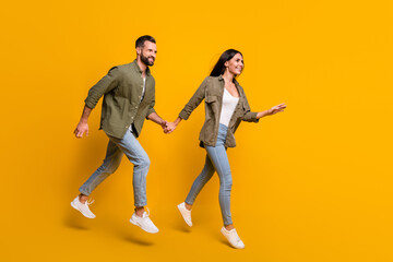Fototapeta na wymiar Full size profile side photo of young couple jump run look empty space discount isolated over yellow color background