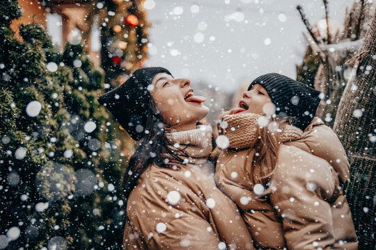 Winter holidays and people concept - happy morther and little daughter choosing christmas tree at street market. Happy family buys a Xmas tree.