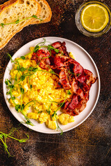 Traditional breakfast scrambled eggs with fried bacon