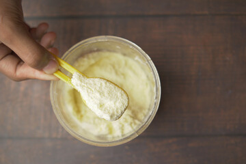 Close up of baby milk powder and spoon on tile background.