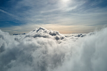 Aerial view from airplane window at high altitude of earth covered with white puffy cumulus clouds