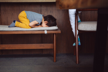 Niño triste y solitario escondido llorando, regañado, castigado y solo, escondiéndose en una...