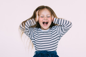 Portrait of little girl holding hands on head, screaming with opened mouth and crazy expression. Surprised or shocked face