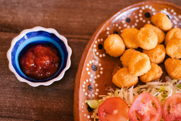 Palomitas de pollo con ensalada y contenedor con salsa catsup