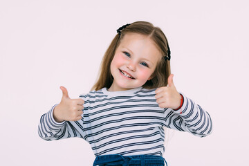 Portrait of a small girl showing thumbs up isolated one white