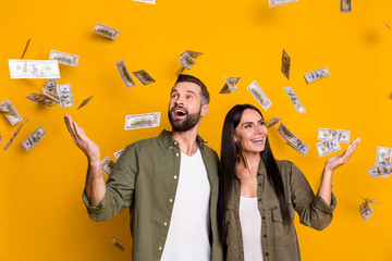 Photo of impressed millennial brunet couple catch money wear shirts isolated on yellow background