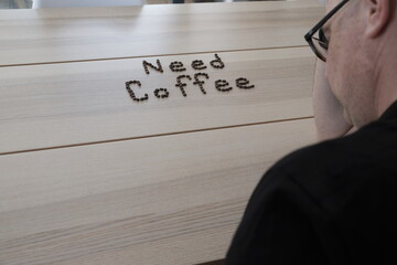 Need coffee sign person leaning on hand as tired