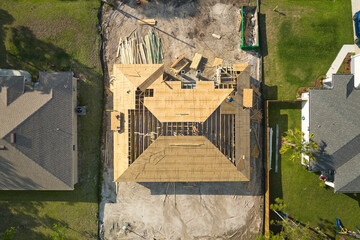 Aerial view of suburban private house wit wooden roof frame under construction in Florida quiet rural area