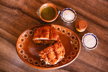 Pambazo partido en dos con salsa, crema y queso 
