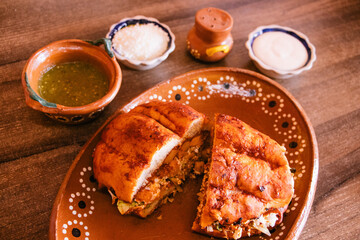 Pambazo partido a la mitad sobre plato de barro 