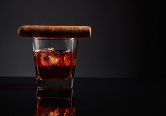 Glass of whiskey with ice and cigar.