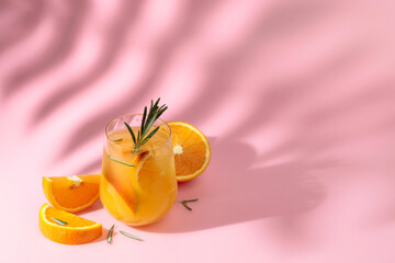 Fototapeta na wymiar Summer cocktail with orange, rosemary, and ice.