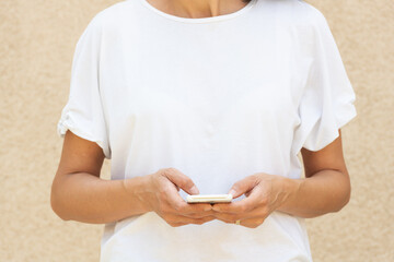 Woman in her forty's using a smartphone with white t-shirt for background or presentation and with large copy space