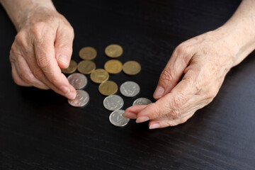 Elderly woman counts russian rubles in coins, wrinkled female hands close up. Concept of poverty in...