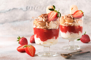 Strawberry tiramisu. Traditional Italian dessert tiramisu in glass with fresh strawberry and mint leaves on old gray concrete background table background. Copy space. Food background.