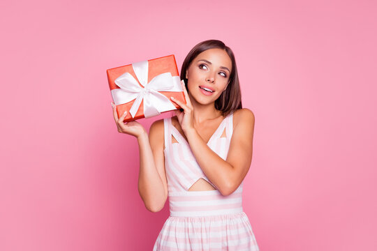 Photo of shiny thoughtful young lady dressed summer clothes holding gift looking empty space isolated pink color background