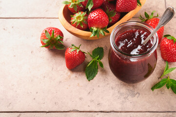 Strawberry jam. Strawberry jam in glass jar with fresh berries plate on an old cracked tile table background, closeup. Homemade strawberry fruity jam. Top view with copy space.