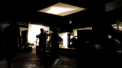Low key silhouette lighting of VDO production behind the scenes which film crew team are setting up...