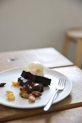 Brownies with dried fruits and ice cream on wood background
