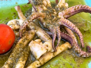 Close up image of grilled squid with olive oil and herbs