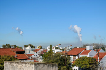 contamination and air pollution. Columns of smoke and smog in the sky above the roofs of houses