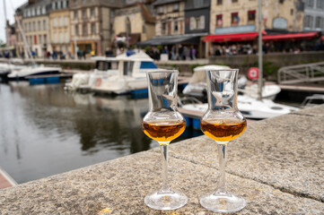 Tasting of apple calvados drink in old Honfleur harbour with boats and old houses on background, Normandy, France