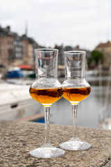 Tasting of apple calvados drink in old Honfleur harbour with boats and old houses on background, Normandy, France