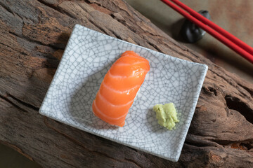 Japanese food salmon sushi in plate has chopsticks on wood background