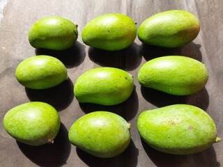 Raw mango in black background. Mango is a popular fruit, it is also called the king of fruits.  Its pickle is very tasty. It is cooked and made into vegetables. Green Mango in black background. 
