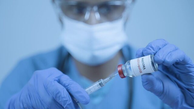 close up shot of doctor with Monkey pox vaccine using with syringe at hospital - concept of treatment and healthcare drug.