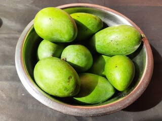 Raw mango in black background. Mango is a popular fruit, it is also called the king of fruits.  Its pickle is very tasty. It is cooked and made into vegetables. Green Mango in black background. 
