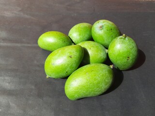 Raw mango in black background. Mango is a popular fruit, it is also called the king of fruits.  Its pickle is very tasty. It is cooked and made into vegetables. Green Mango in black background. 
