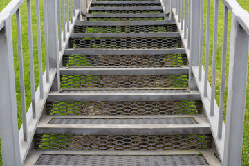 Grey iron staircase with railings on a green grass background