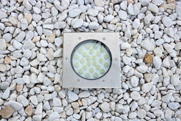Built-in modern round-shaped lamp on white gravel in the garden