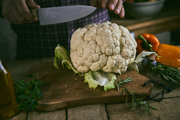 Crop man cutting ripe cauliflower