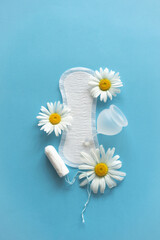 Obraz premium Menstruation period concept. Hygienic white female pad, Menstrual cup and tampon with chamomile flowers. Menstruation, protection. Women's health