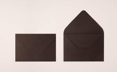 Closed and open black envelope on light background of a milky color