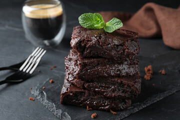 Delicious chocolate brownies with fresh mint served on black table, closeup