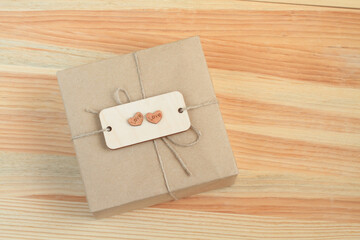 The box, wrapped in rough paper and tied with a rough rope, lies on a wooden table. View from above. Closeup