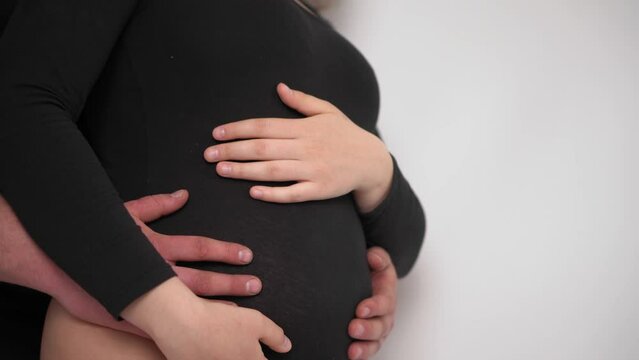 Happy pregnant woman with big belly resting at home. Pregnant young woman with husband expecting a baby. The young family is waiting for replenishment. Young expectant mother caresses her belly.