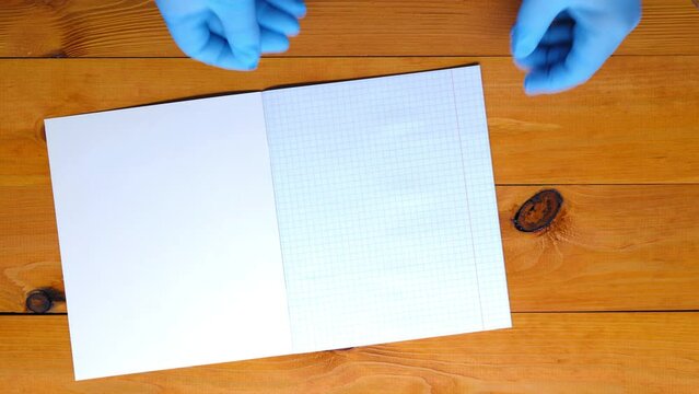 The math tutor is preparing for the lesson. Checkered maths school notebook, ruler, triangle, protractor, pen, pencil on the table. Back to school. Empty page on the school desk. Copy space for text