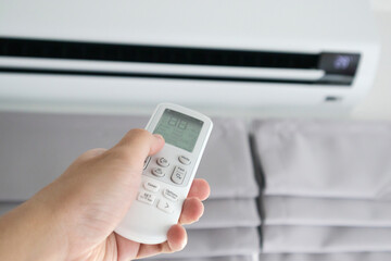 Hand with remote control directed on air conditioner