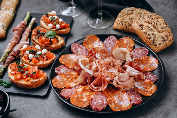 Food antipasto prosciutto ham, salami, olives and bread sticks and Tomato and basil bruschetta Charcuterie board. Two glasses of white wine or prosecco