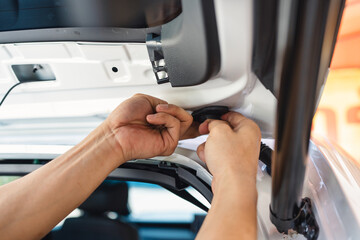 Hand of mechanic using wedge removing and installing a dash cam inside a car at workshop