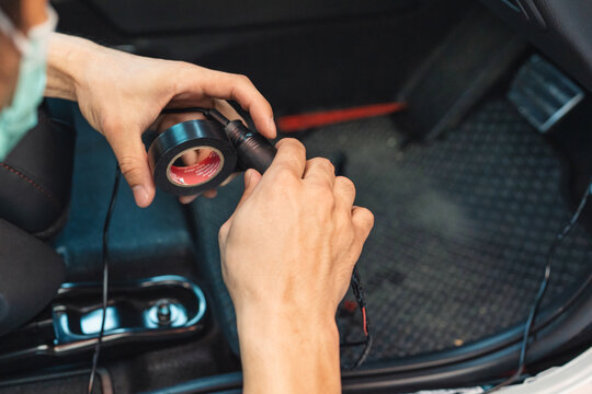 Hand Of Mechanic Using Duct Tape Wrapping Wire Of Car To Install Device