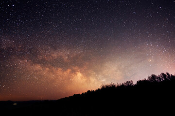 Beautiful bright milky way galaxy at the night sky and hills silhouette. Astronomical background.