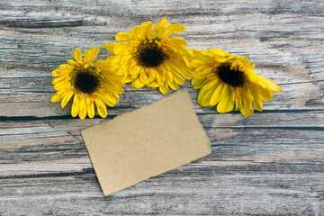 Torn brown paper on wooden surface and sunflower flat lay with copy space.