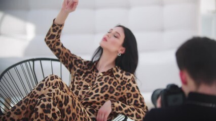 Young attractive model woman in a leopard suit having photoshoot in white studio