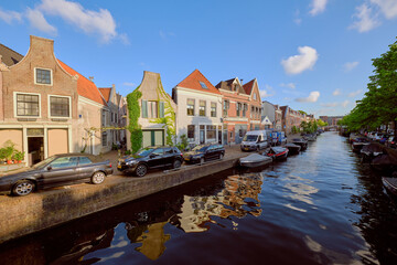 Fototapeta na wymiar HAARLEM, NETHERLANDS - MAY 24, 2022: Clear reflections of canal-side houses on the Burgwal canal on a sunny evening.